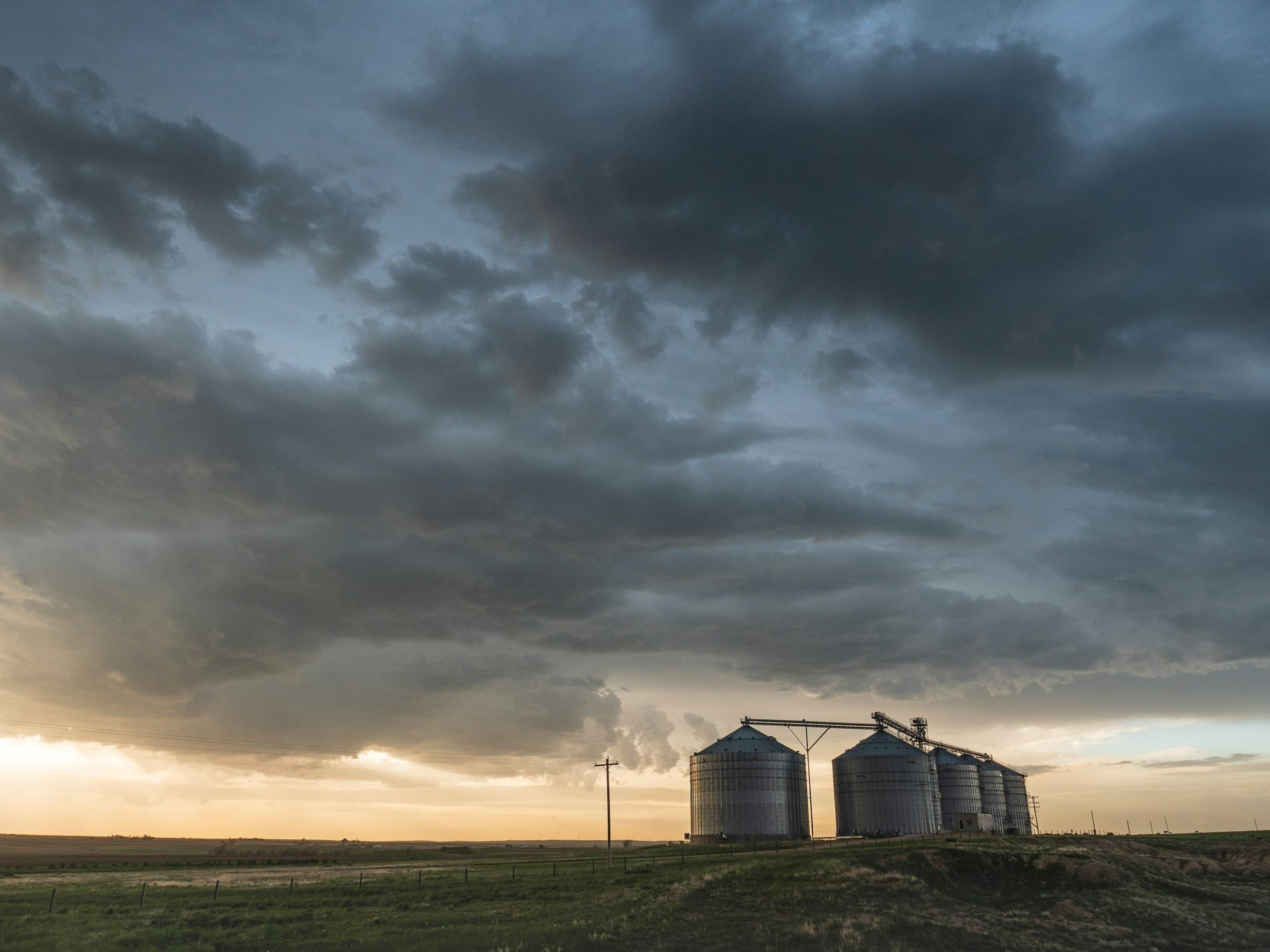 Grain silos standing on open farmland.