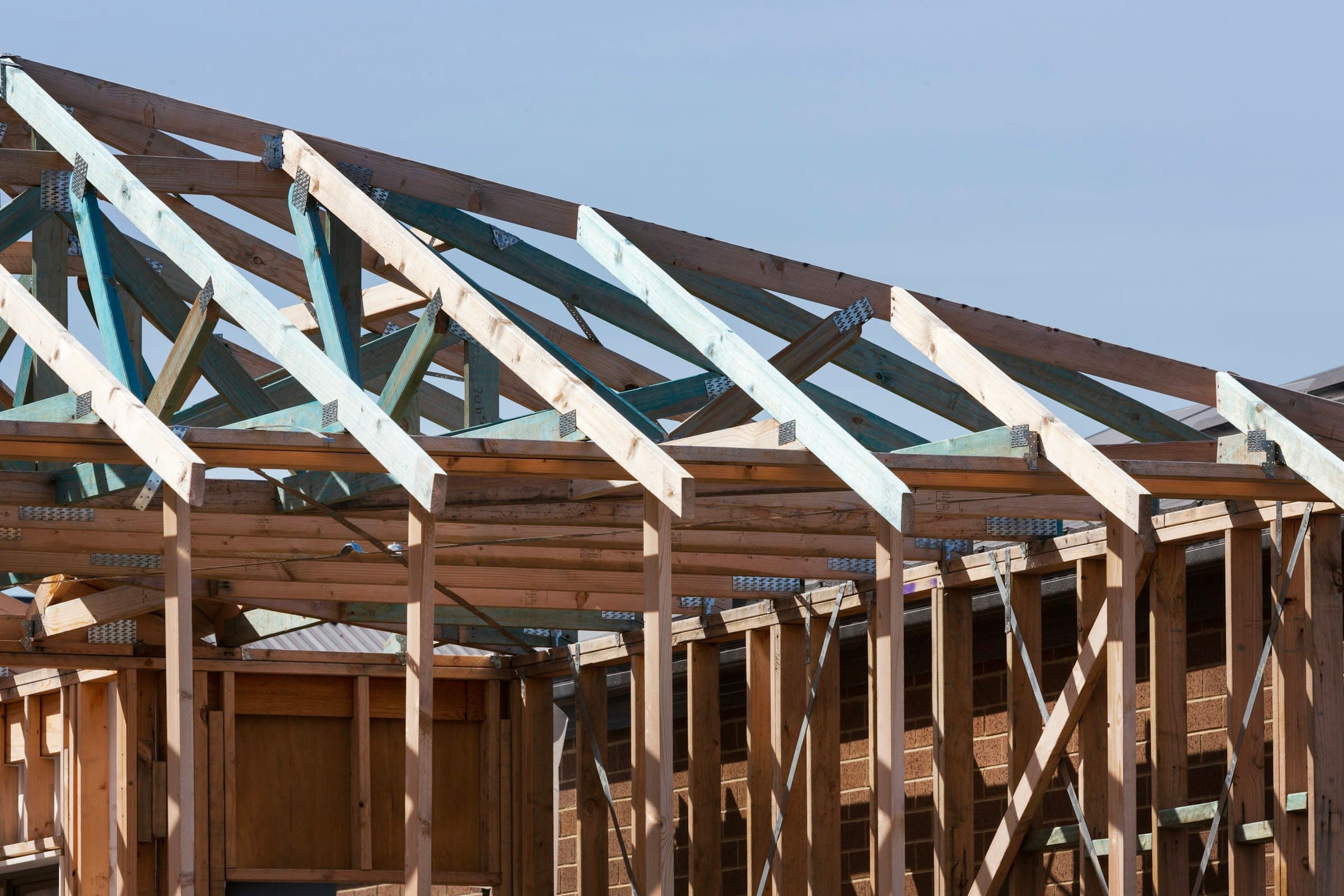 The roof of a house under construction, rafters exposed against the sky.